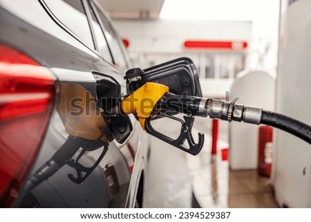 Cropped picture of a fuel nozzle filling a vehicle tank.