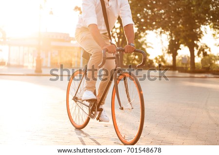 Cropped picture of handsome young african man early morning with bicycle walking outdoors.
