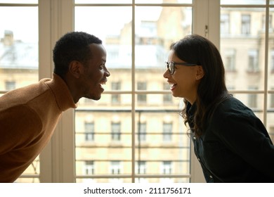 Cropped Picture Of Man And Woman Looking At Each Other With Happy, Surprised And Cheerful Face Expressions Against Wide Window, Celebrating Purchase Of Their Own Property, Female Wearing Glasses