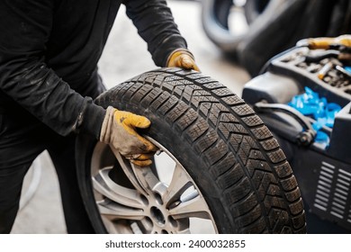 Cropped picture of mechanic holding car wheel at vulcanizing workshop. - Powered by Shutterstock