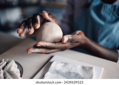 Cropped picture of multicultural craftswoman's hands modeling clay at modern ceramic studio. Close up of african american pottery course student learning clay work and pottery at pottery workshop. - Powered by Shutterstock