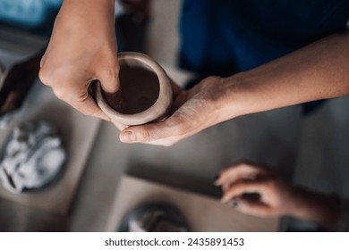 Cropped picture of pottery class teacher making earthenware on pottery class and showing students arts and crafts. Close up of pottery class tutor' hands doing clay work and art making earthenware. - Powered by Shutterstock