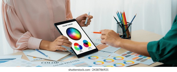 A cropped picture of professional designer selects the color by using color theory and comparing with color wheel on table with designing material and equipment scatter around. Variegated. - Powered by Shutterstock