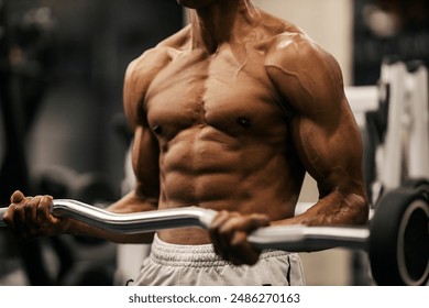 Cropped picture of shirtless muscular multicultural bodybuilder doing biceps curls at gym. - Powered by Shutterstock