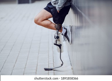 Cropped picture of sportsman with artificial leg standing against the wall and holding hands in pockets. - Powered by Shutterstock