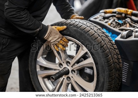 Cropped picture of vulcanizing worker using balancing equipment for car wheel.
