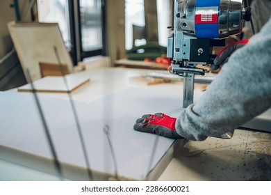 Cropped picture of a worker's hands operating a foam cutter at the furniture workshop. Close up picture of hands and foam cutter at the workshop. A craftsman is making handmade furniture. - Powered by Shutterstock