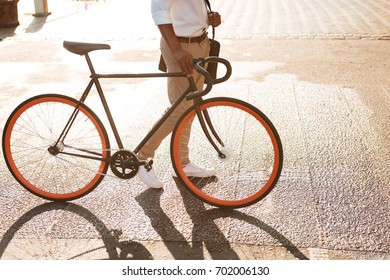 Cropped picture of young african handsome man early morning with bicycle walking outdoors. - Shutterstock ID 702006130