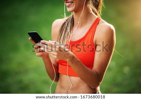 Similar – Woman with earphones listening music in smartphone