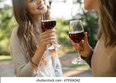 Cropped Picture Of Young Two Women Outdoors In Park Drinking Wine.