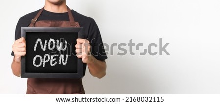 Cropped portrait of Asian barista man holding a blackboard holding a blackboard that says 