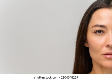 Cropped portrait of attractive asian woman with naked shoulders looking at the camera. Half face of serious beautiful female with smooth face skin and natural make-up, straight healthy hair isolated