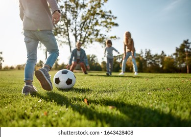 Cropped Portrait Of Cheerful Little Girl Playing Football With Her Family In The Park On A Sunny Day. She Is Having Fun While Running The Ball. Family, Kids And Nature Concept. Horizontal Shot.