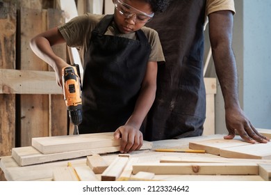 Cropped Portrait Of Cute African-American Boy Building Birdhouse In Workshop With Dad