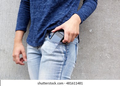 Cropped portrait of female hand taking out mobile phone from her jeans pocket