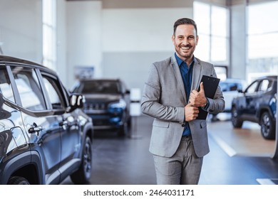 Cropped portrait of a handsome young male car salesman working on the showroom floor. Happy salesperson standing in a car showroom looking at camera. - Powered by Shutterstock