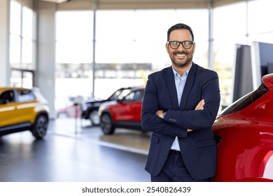 Cropped portrait of a handsome young male car salesman working on the showroom floor. Happy salesperson standing in a car showroom looking at camera. - Powered by Shutterstock