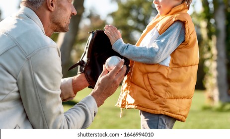 Cropped Portrait Of Man With Kid. Father Holding Baseball Glove While Explaining Rules Of The Game To His Little Boy. Family, Kids And Nature Concept. Horizontal Shot. Side View