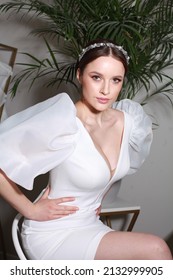 Cropped Portrait In Modern Interior. Bride Posing In Wedding Designer Dress With Puffy Short Sleeves. Delicate Wedding Hair Band Accessory. Fresh Design Elements With Hint Of Nostalgia 80's 90's