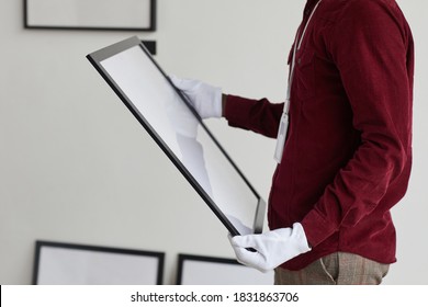 Cropped Portrait Of Unrecognizable Man Wearing Gloves Holding Painting Frame While Standing Against White Wall In Art Gallery, Copy Space