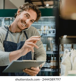 Cropped portrait of young handsome bartender shop assistant owner barman waiter barista talking on the phone taking orders with notepad in his hands in cozy coffee shop - Powered by Shutterstock