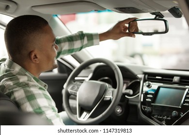 Cropped Rear View Shot Of A Male Driver Adjusting Rear View Mirror, Sitting At His New Automobile. Man Buying New Car At The Dealership Salon, Examining Interior Of An Auto. Safe Driving, Concept