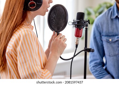 Cropped Redhead Woman Singing To The Microphone In Studio. Female Vocal. Side View. Caucasian Adult Woman Performer Preparing For Concert In Bright Studio Room, Recording Song.