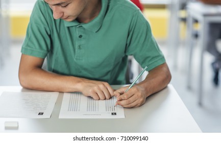 Cropped schoolboy taking an exam at classroom.