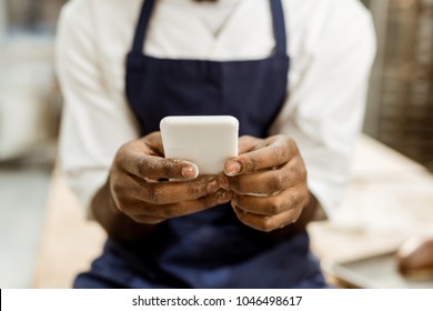 cropped shot of african american baker with hands covered in flour using smartphone - Powered by Shutterstock