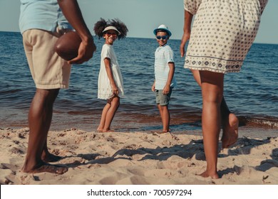 Cropped Shot Of African American Family With Two Children Playing With Rugby Ball On Beach 