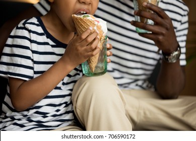 Cropped Shot Of African American Father And Son Eating Ice Cream In Cafe