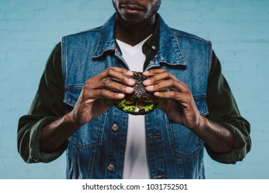 Cropped Shot Of African American Man Holding Tasty Black Burger
