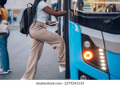 Cropped shot of an african american woman entering the bus while standing at the station.Black unrecognized female get in the public transportation while going to work or school. Copy space.
