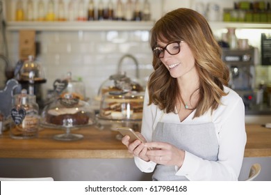 Cropped shot of an attractive cafe owner standing by the counter and text messaging. Small business. 