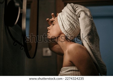 Cropped shot of an attractive woman examing her face skin in front of the bathroom mirror.