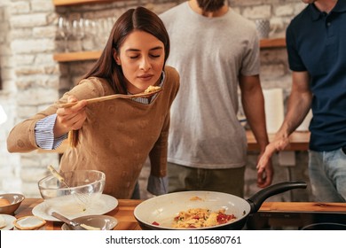 Cropped shot of an attractive young brunette tasting food while cooking