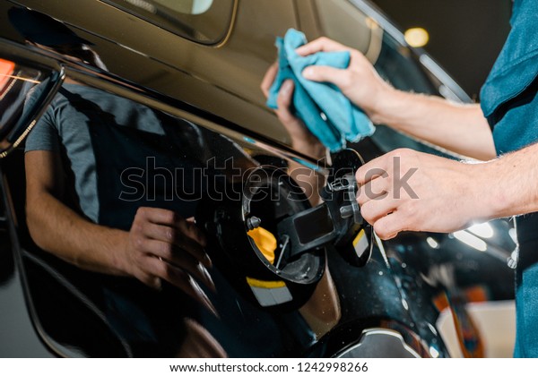cropped shot of auto mechanic cleaning car with rag\
at auto repair shop