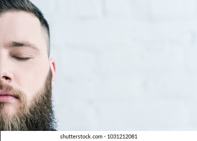cropped shot of bearded man with eyes closed against white brick wall - Shutterstock ID 1031212081