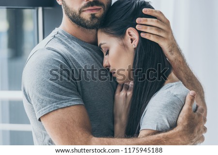 cropped shot of bearded man hugging and supporting young sad woman