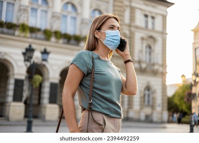 Cropped shot of beautiful businesswoman talking on the phone while wearing face mask outdoors. - Shutterstock ID 2394492259