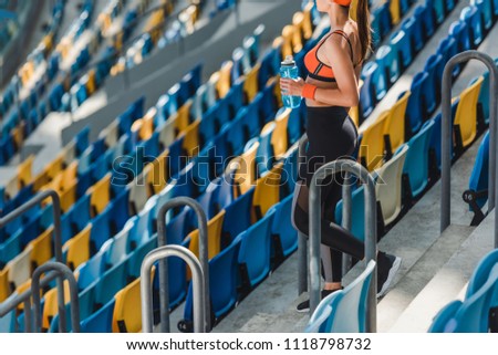 cropped shot of beautiful young woman standing on tribunes at sports stadium