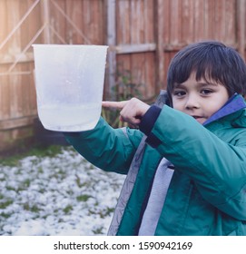 Cropped Shot Boy Holding Measuring Jug Pointing At Level Of Rain Collected In Garden. 6 Year Old Child Measuring Rainfall For School Science Project About Weather And Climate Change. Education Concept