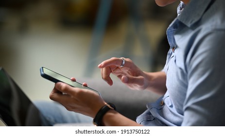 Cropped shot of businessman using mobile phone while sitting in modern office.