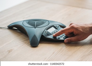 Cropped Shot Of Businessman Using Speakerphone At Workplace