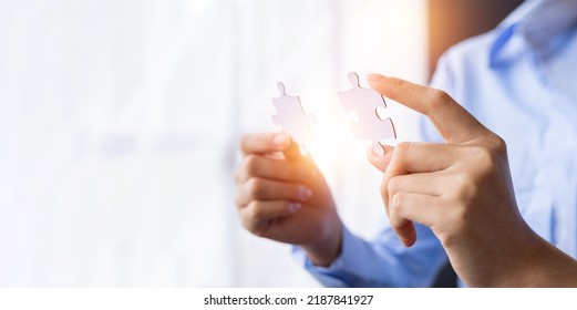 Cropped shot of Businesswoman hand connecting jigsaw puzzle with sunlight effect, Business solutions, success, and Assembling jigsaw pieces, strategy ideas.