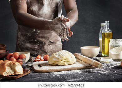 Cropped Shot Of Busy African Male Cook Kneads Dough, Prepares To Show His Culinary Talents, Poses Near Workplace With Ingredients, Isolated Over Black Background. Cooking And People Concept.