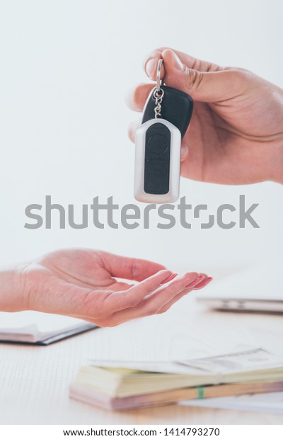 cropped shot of car dealer giving car keys to\
customer in office