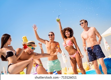 Cropped shot of chilling, dancing international youth, enjoying on resort beach pool sunny disco, in diverse trendy fashionable bikinies, spectacles, caps, with drinks, celebrating holiday
