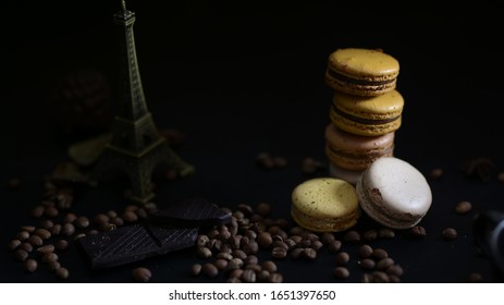 Cropped shot of coffee and chocolate macarons on coffee bean with Eiffel Tower model decorated on dark background