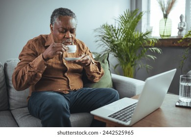 Cropped shot of a contemplative senior man seating alone in his home and enjoying a cup of coffee. Senior Black Man Enjoying a Cup of Coffee at Home - Powered by Shutterstock